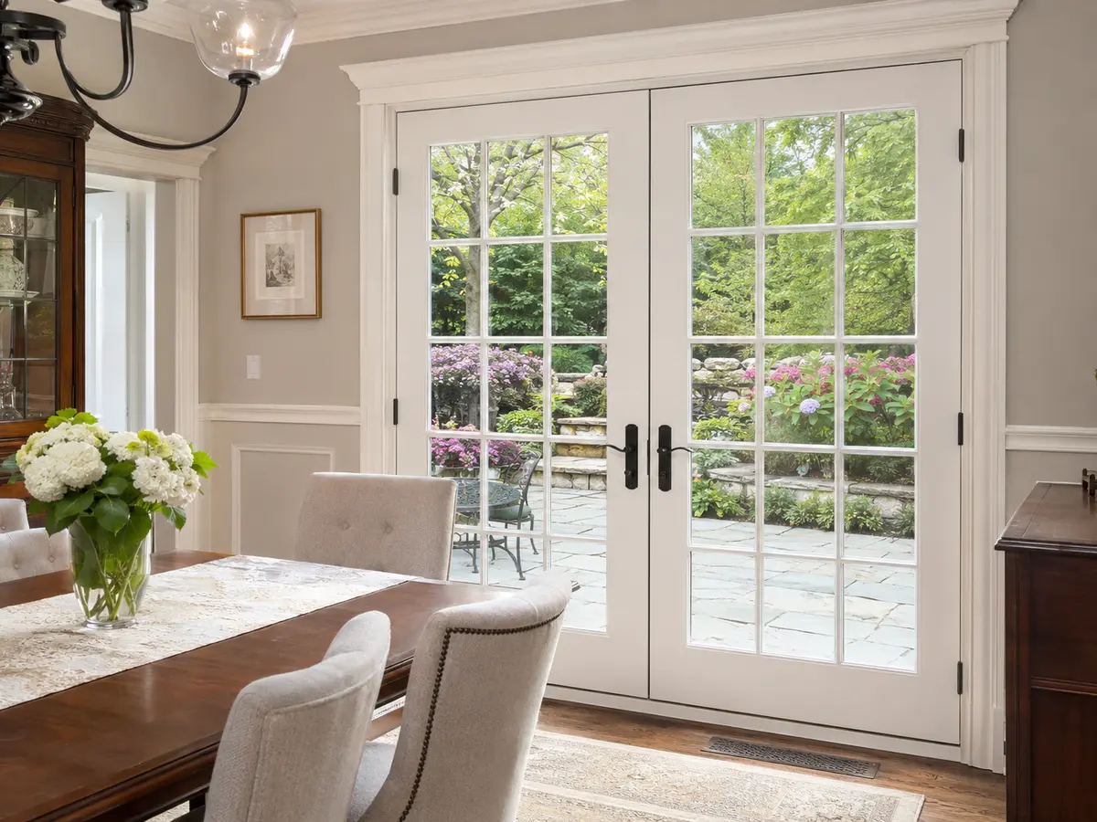 Dining room with classic white French double doors opening to a garden